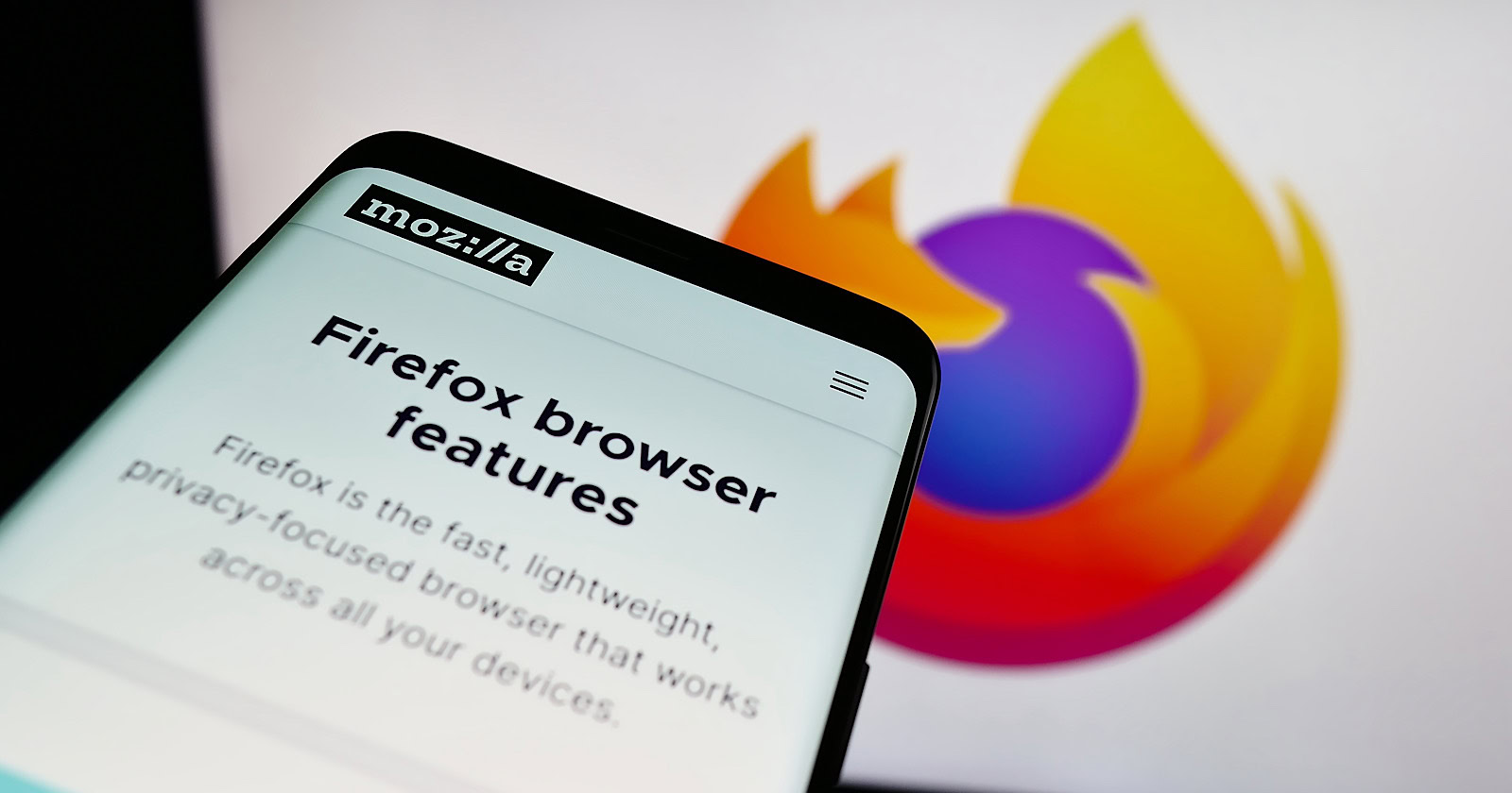 Smartphone with webpage of open-source web browser Mozilla Firefox on screen in front of logo.