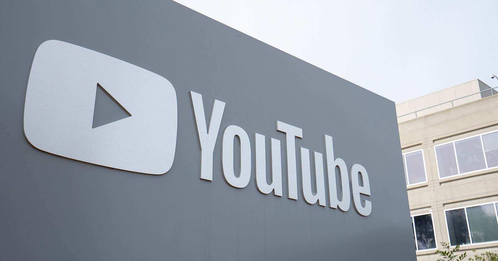 A large YouTube Shorts logo on the exterior wall of a building, featuring a bold, white play button inside a gray rectangle with the word "YouTube" next to it.